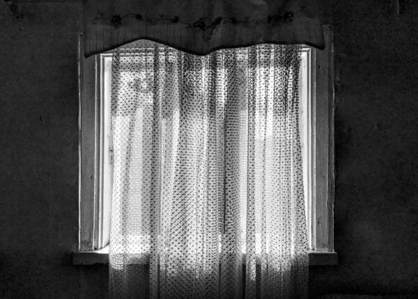 A monochrome image of a window adorned with curtains