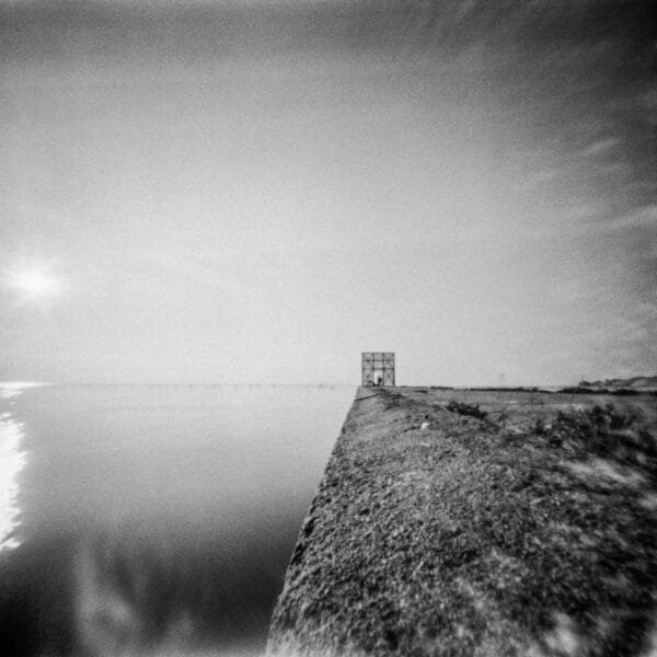 A monochrome image of a waterfront building, showcasing its architectural beauty and serene location