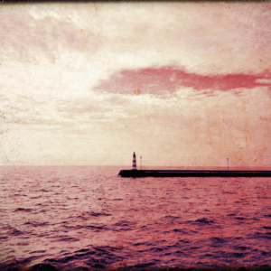 A lighthouse in the distance surrounded by red water